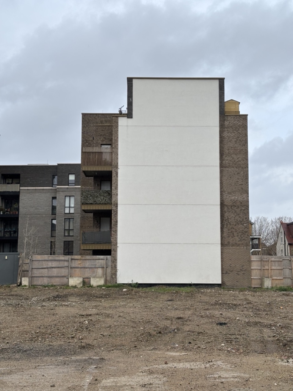 Photograph of building exterior and cleared site. Large white panels cover the building facade